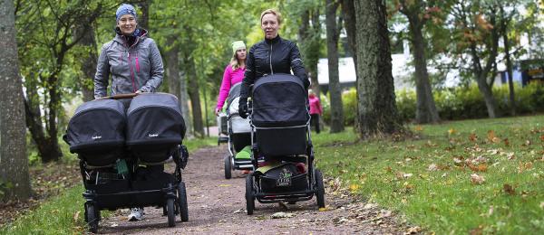 Bilden visar mammor med barnvagnar promenerandes en höstdag.