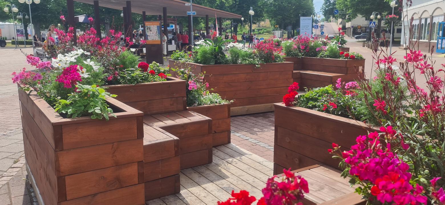 massiva utemöbler i trä med blommor intill torget