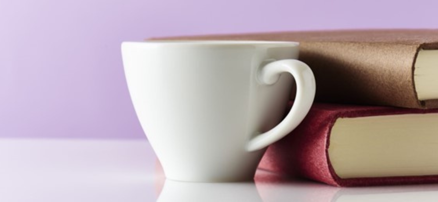 En kaffekopp och en hög med böcker