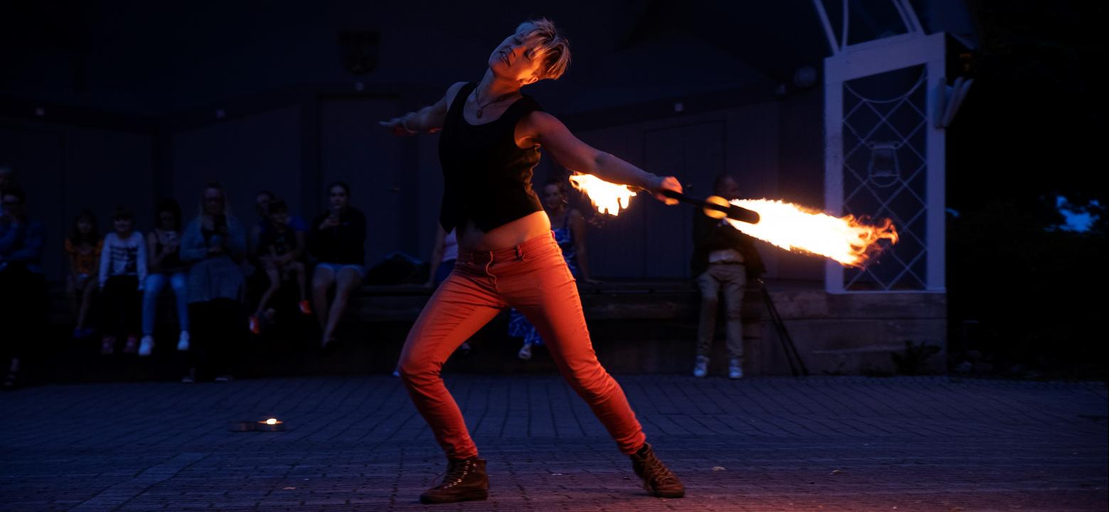 Kvinna som uppträder i mörkret med eldshow på torget i Mariehamn