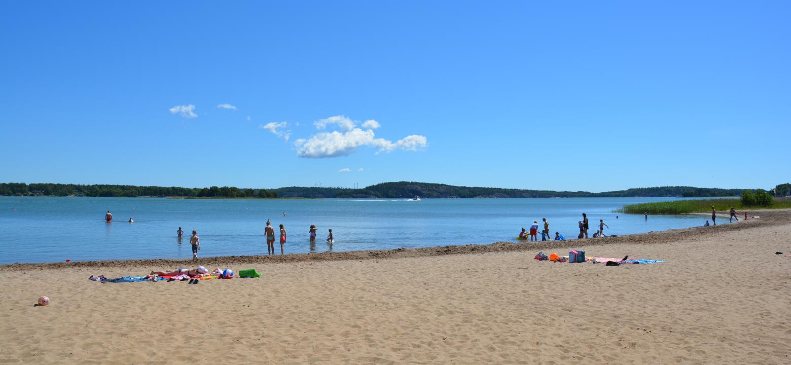 Foto av en sandstrand med hav och himmel i bakgrunden