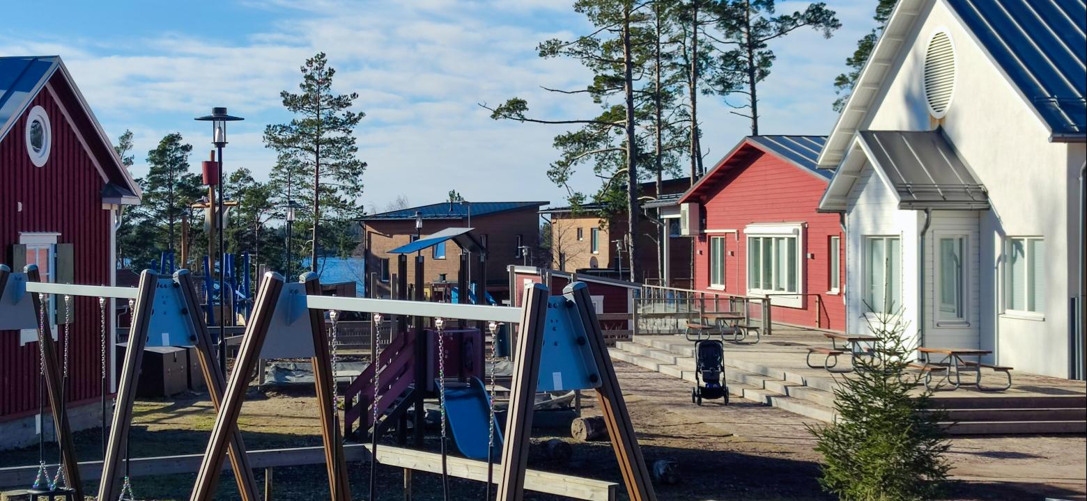 Bilden visar att Skutans daghem och en del av gården som gungor och uteplats, i bakgrunden ses havet och bostadshus.