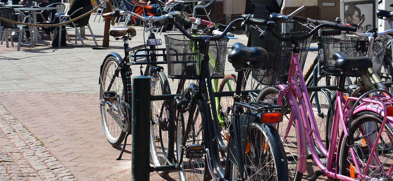 Bilden visar cykelställ och många cyklar på centrala Troggatan, i bakgrunden syns en av uteserveringarna.