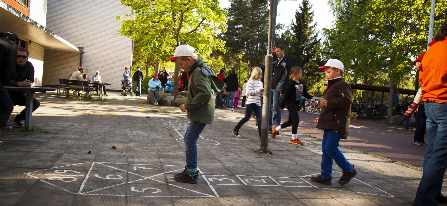 Barn hoppar hage utanför skolbyggnad
