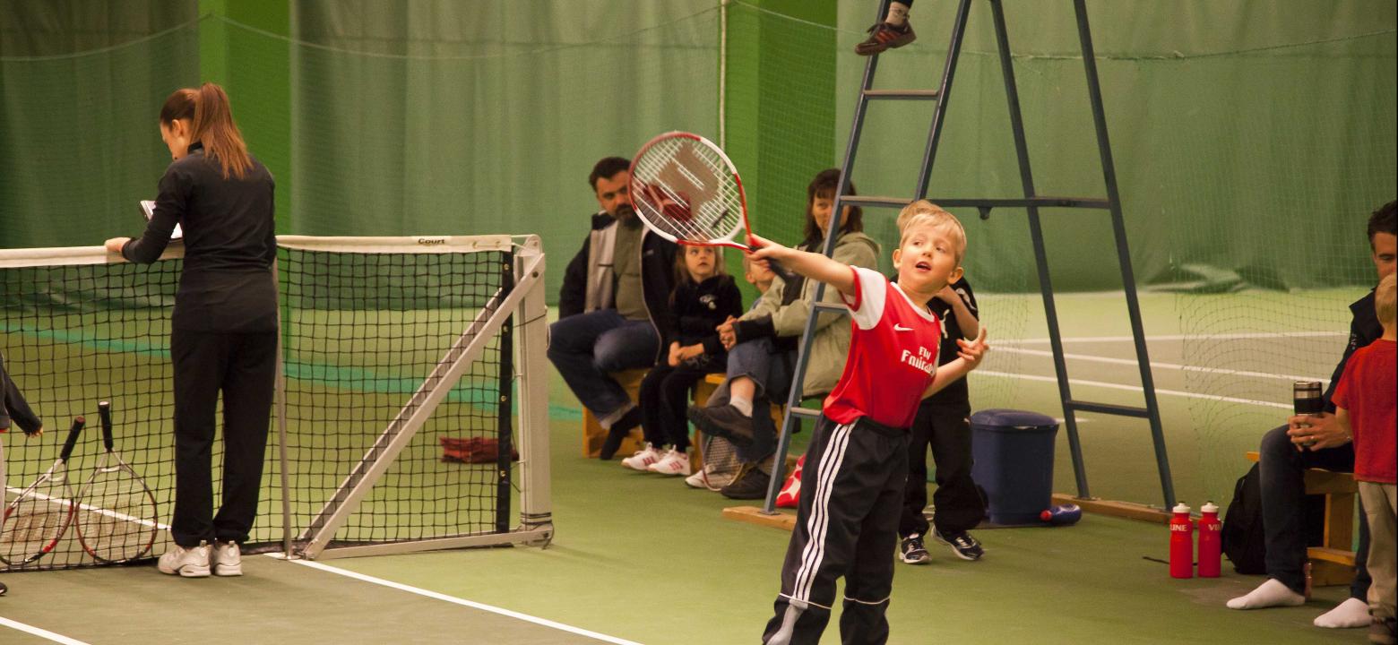 Bilden visar en pojke med tennisracket inne i Bollhalla