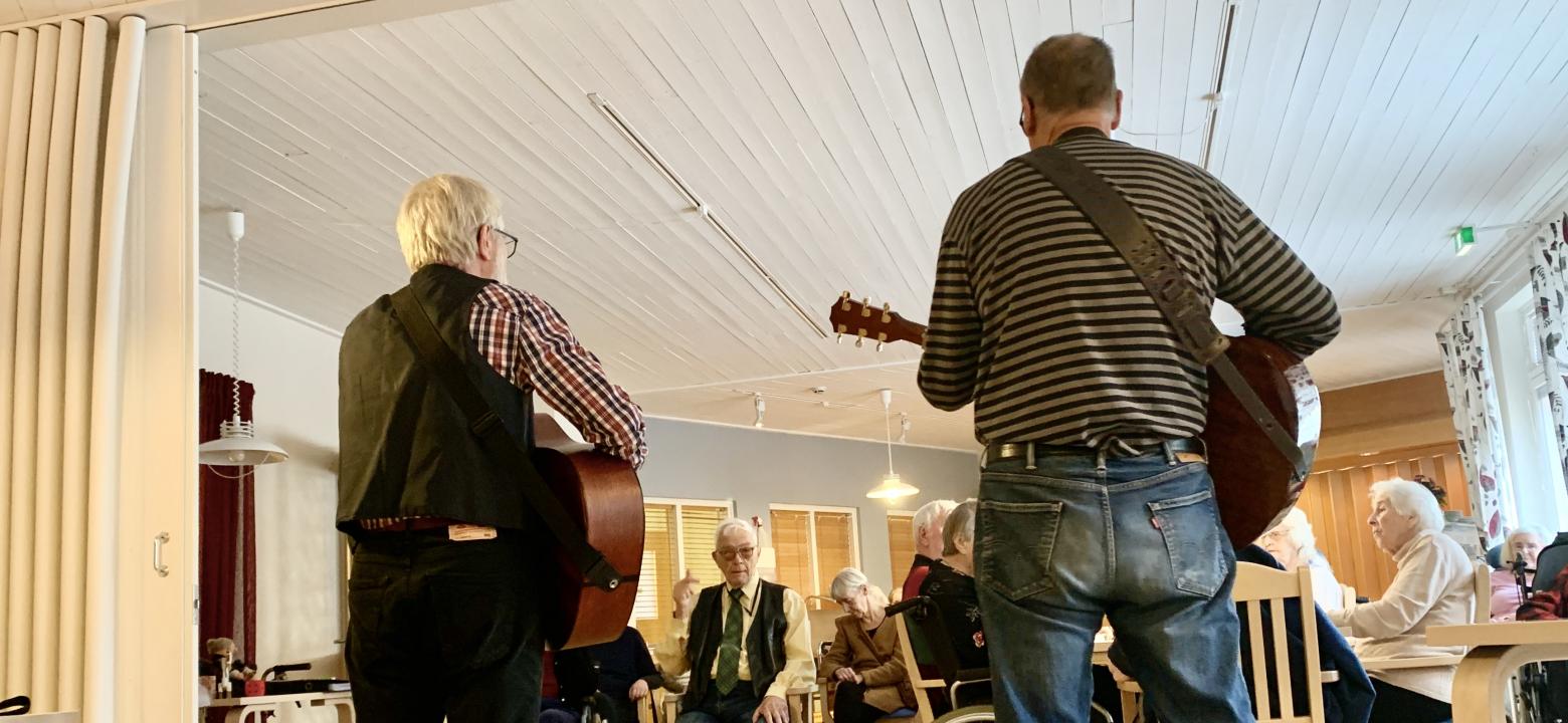 Två män spelar gitarr i Odalgårdens matsal