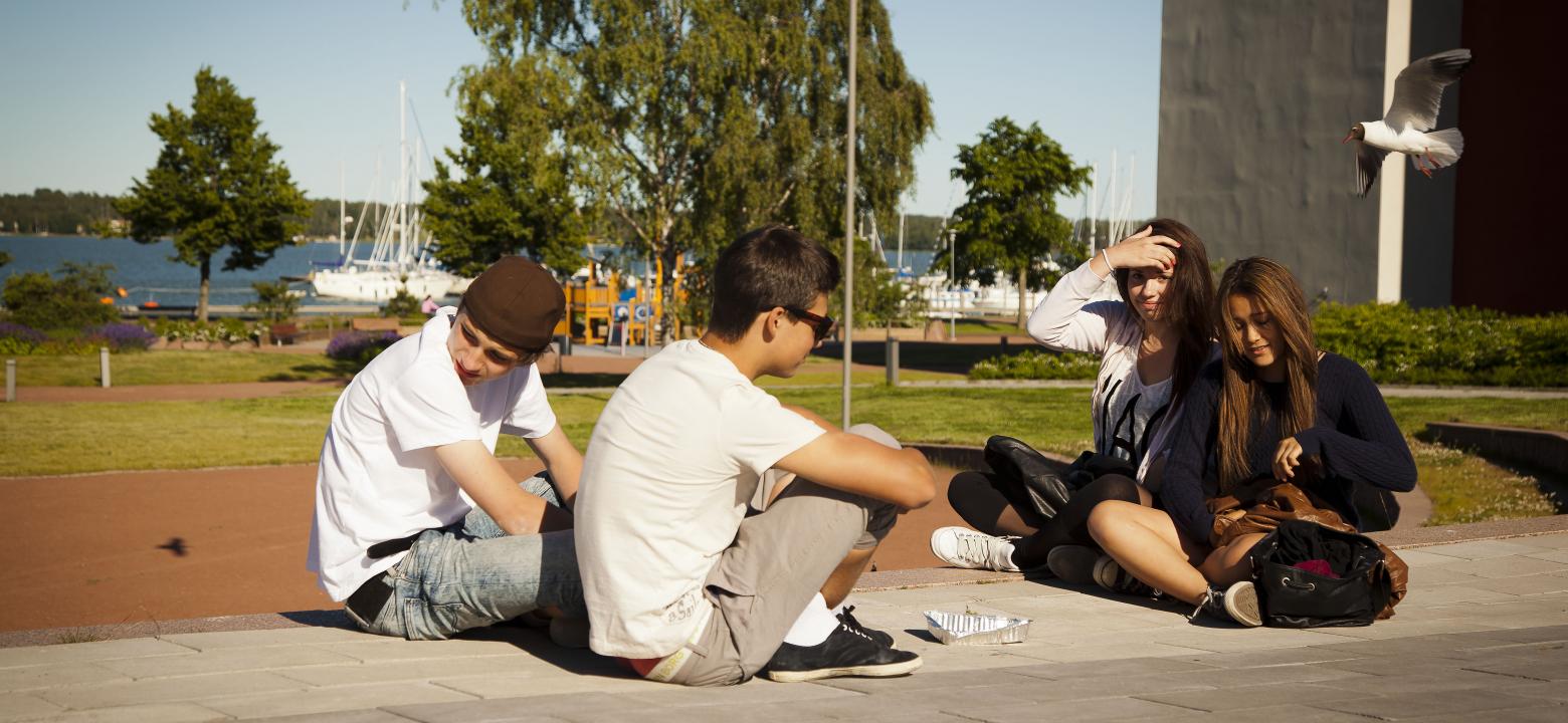 Fyra ungdomar vid Miramarparken och småbåtshamnen i bakgrunden