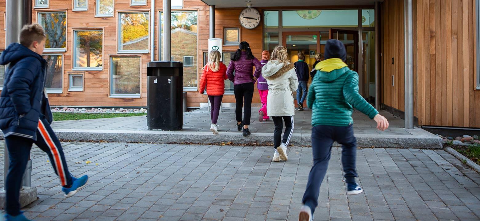 Bilden visar elever som springer in i skolan