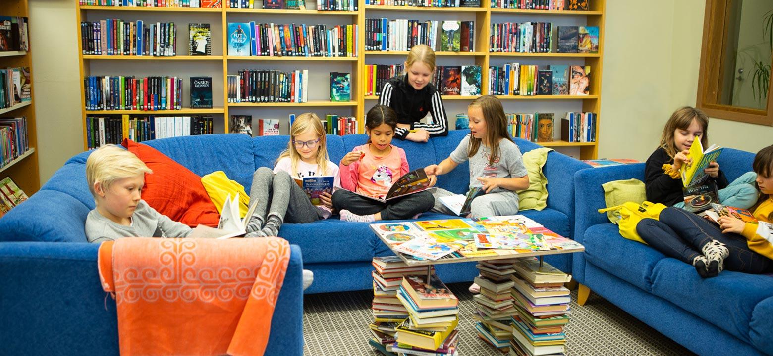 Bilden visar många elever som läser böcker i de stora blå sofforna i Övernäs skolas bibliotek