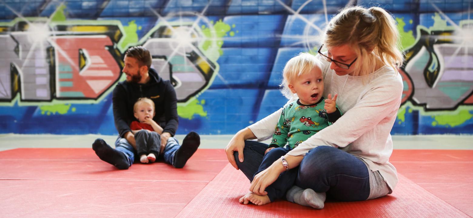 Bilden visar en manlig och en kvinnlig i personalen på ett dagis med varsitt barn i famnen