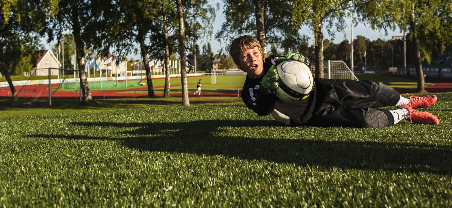 BIlden visar en pojke som fångar en fotboll 
