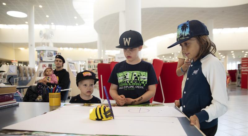 Tre barn testar att programmera en Bee-bot.
