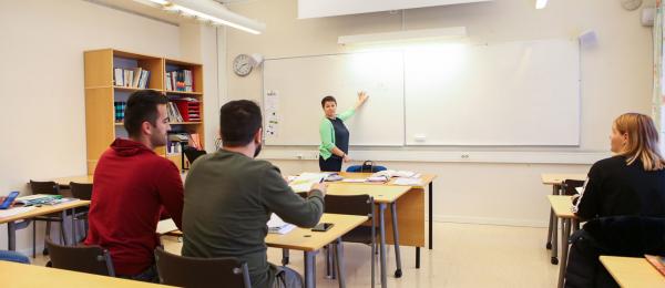 Bilden visar studerande i ett klassrum som lyssnar på läraren