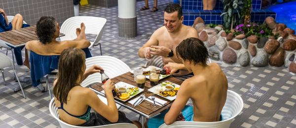 Bilden visar personer i badkläder som äter i delen av restaurangen som finns i badet.
