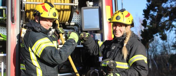 Bilden visar en manlig och en kvinnlig brandman