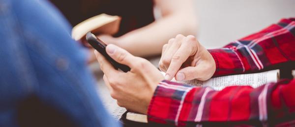 Bilden visar en person som sitter med sin mobil i handen