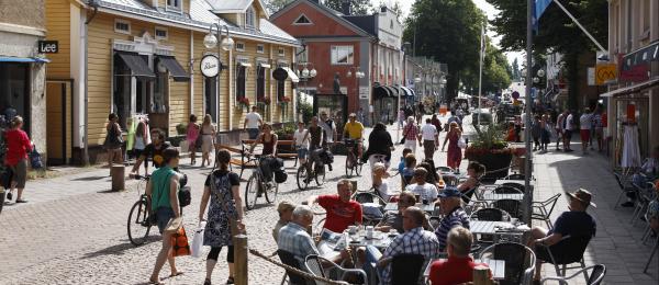En gågata med fotgängare, cyklister och cafébesökare.