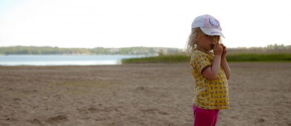 flicka med keps på Nabbens sandstrand